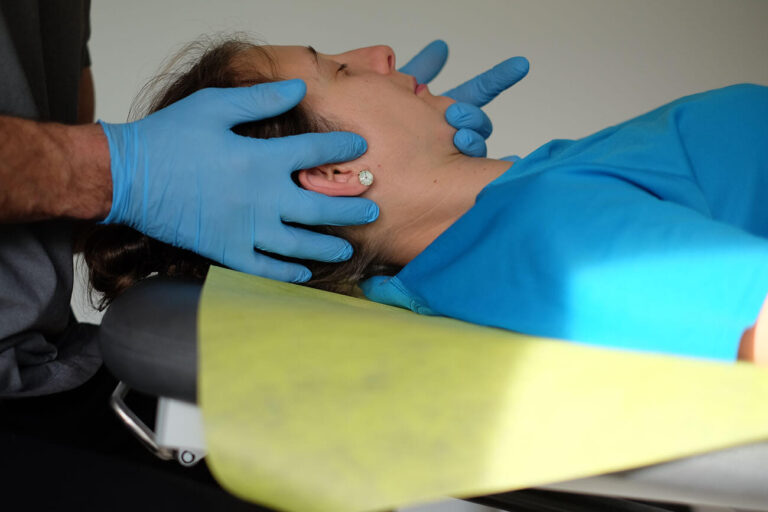 Therapeut behandelt eine Patientin am Kiefer